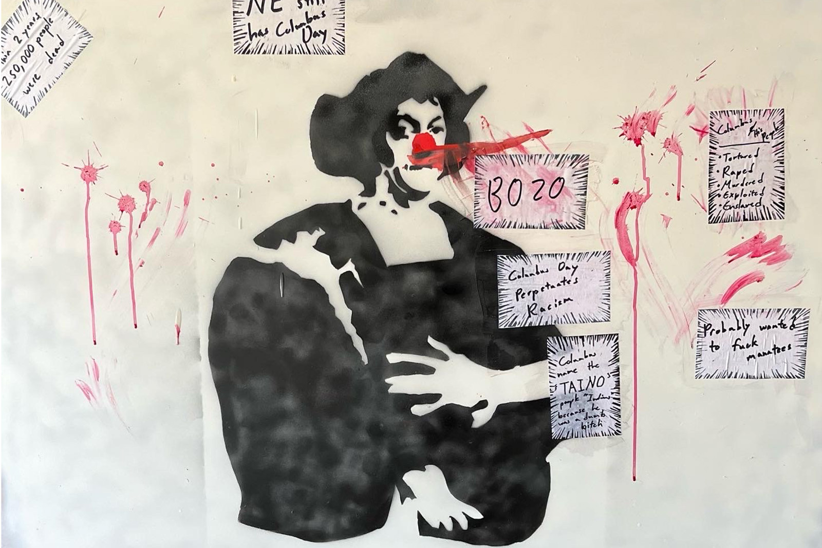 A black and white stencil of christopher columbus with a red clown nose with small wheat pasted messages around it