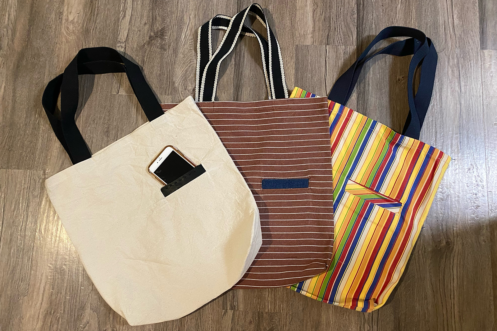 A set of three tote bags with cell phone pockets on the front