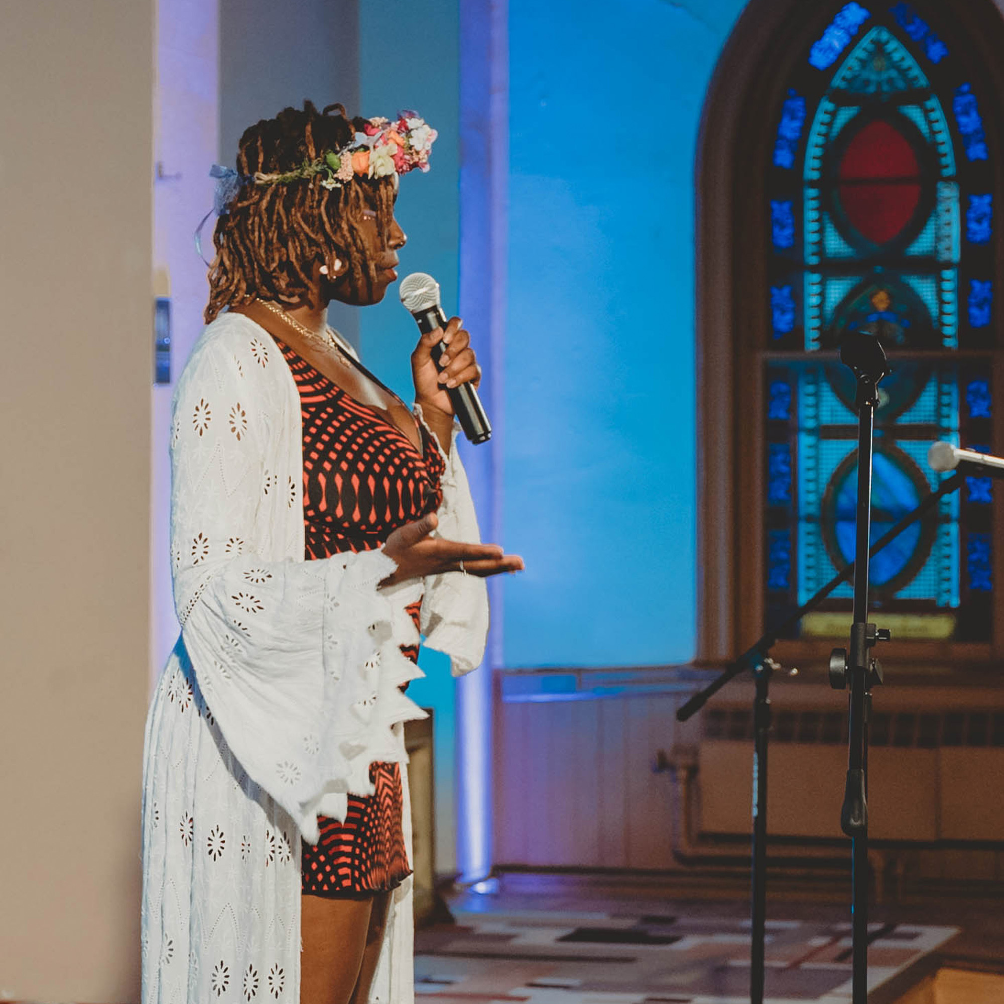 Artist Alajia Mc Kizia stands in profile holding a microphone