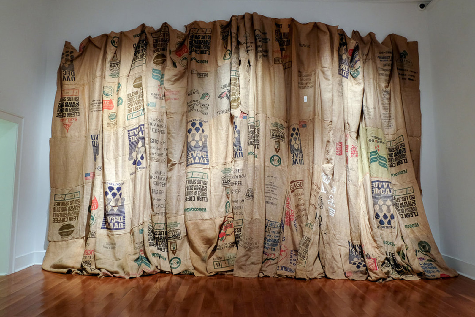 Installation work by Kaneem Smith Burlap bags are sewn together and hung against a white wall