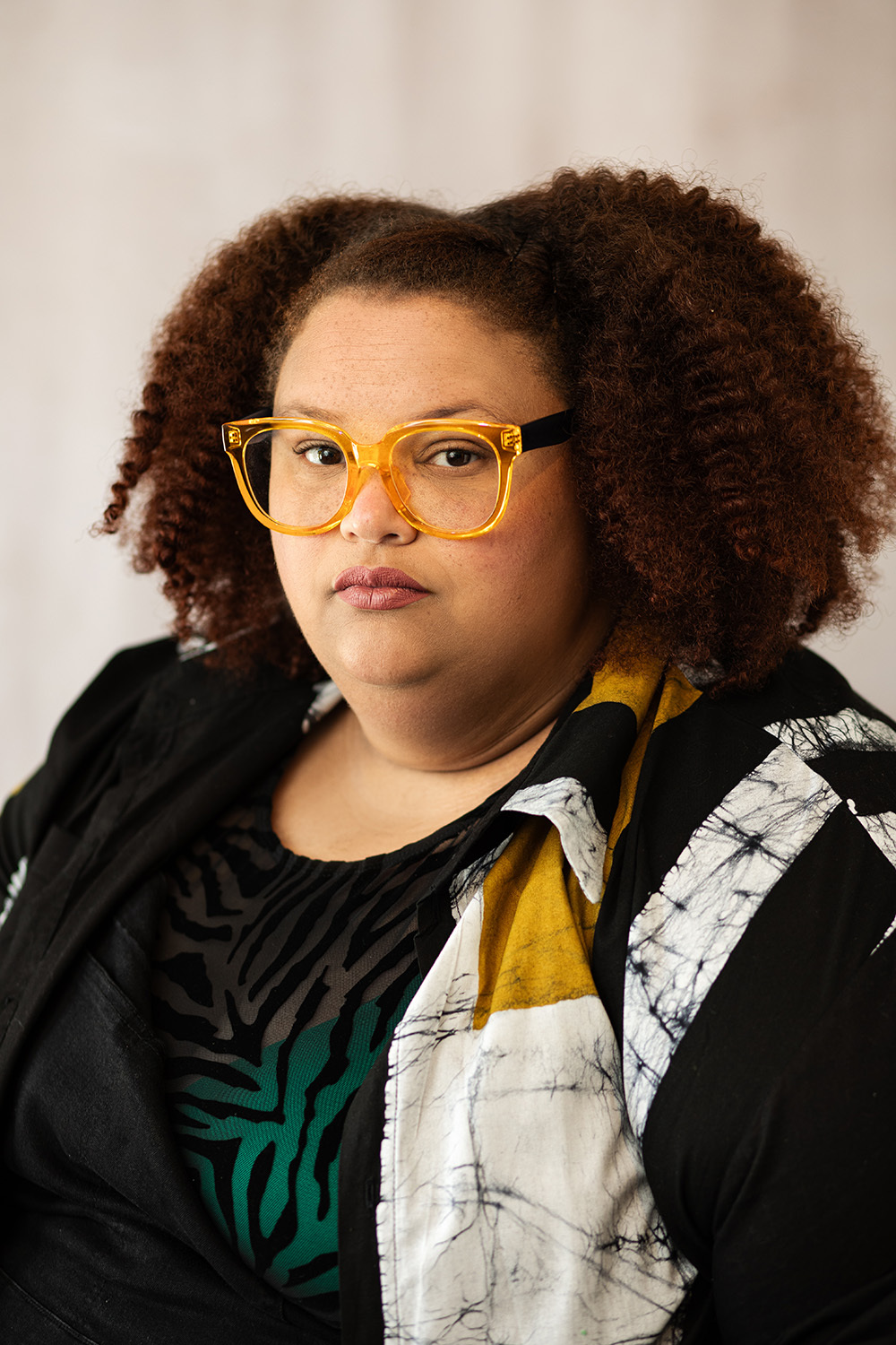 Portrait of artist April Bey She wears yellow glasses and is looking at the camera